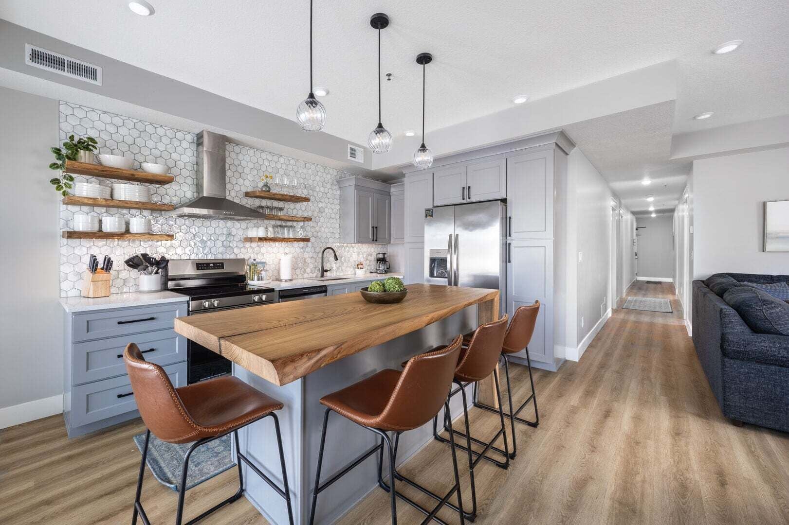 A modern kitchen with a central island, bar stools, and a dining table.