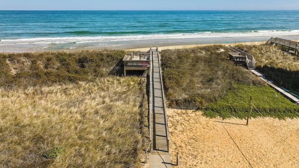 A beach with a wooden boardwalk leading to a beach entrance. - 4203 - Here Comes the Sun - Duck Oceanside Condo | Community Pool & Beach (Duck)
