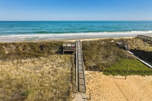 A beach with a wooden boardwalk leading to a beach entrance.