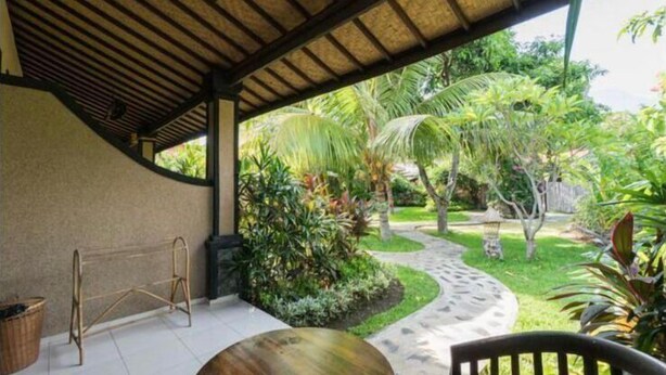 A covered patio area with a thatched roof, a small table, and chairs. - Pondok Rahayu Guest House (Pemuteran)