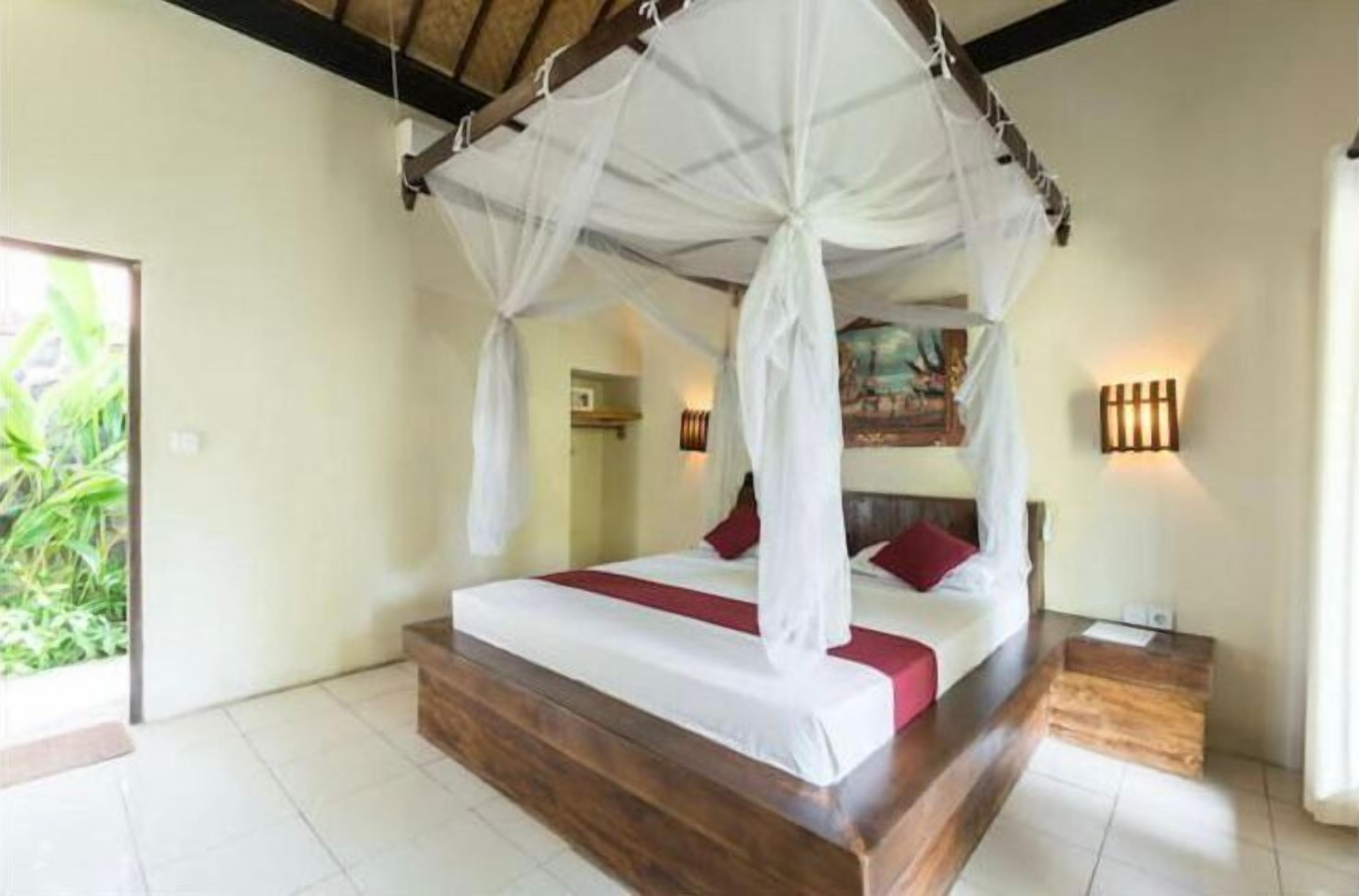 A bedroom with a four-poster bed, a wooden headboard, and a nightstand with a lamp.