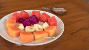 A plate of assorted fruits including watermelon, dragon fruit, and bananas on a wooden table. - Pondok Rahayu Guest House (Pemuteran)
