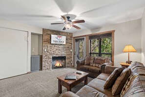 A living room with a stone fireplace, a ceiling fan, a sofa, and a coffee table.