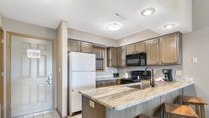 A compact kitchen with a refrigerator, microwave, stove, and wooden cabinets. - Lakefront 2 BD/2BA, Sleeps 8 Resort Amenities and Ticket Savings!! (Branson)