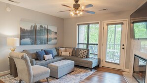A living room with a sectional sofa, a chair, a fireplace, and artwork on the wall. - Modern Walk-In Lakefront Condo, Sleeps 8.  Ticket Deals and close to Silver Dollar City! (Branson)