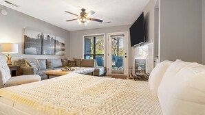 A bedroom with a large bed, a sofa, a desk, and a TV. - Modern Walk-In Lakefront Condo, Sleeps 8.  Ticket Deals and close to Silver Dollar City! (Branson)