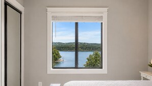 A bedroom with a large window, a bed, and a nightstand. - Walk to Table Rock Lake • Family Friendly • Minutes to SDC (Branson)