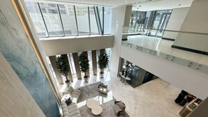 En rymlig entréhall med högt i tak, en central sittgrupp med ett runt bord och ett glasräcke med utsikt över den nedre våningen.