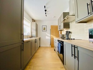 Una cocina moderna con gabinetes grises, una encimera de madera y un horno empotrado.