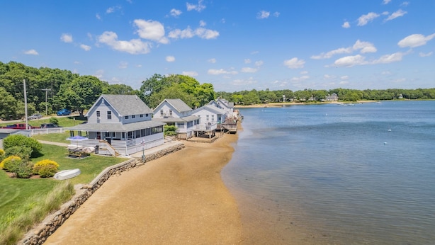 A waterfront property with multiple houses, a sandy beach, and a calm lake.