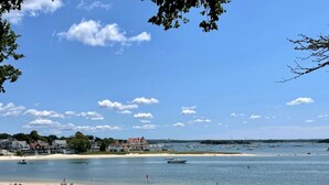 A beach with houses in the background and boats on the water.