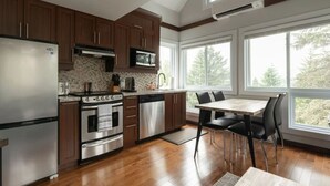 A modern kitchen with wooden cabinets, stainless steel appliances, and a dining area with a table and chairs.