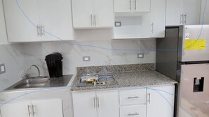 A modern kitchen with white cabinets, a granite countertop, a stainless steel sink, and an LG refrigerator.
