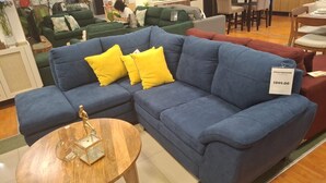 A blue sectional sofa with yellow cushions in a furniture store.