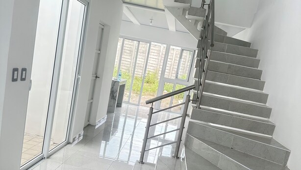 A modern staircase with a metal handrail, leading to a glass door.