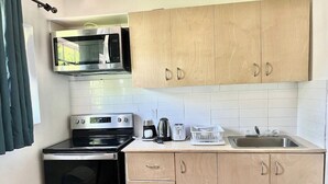 Une cuisine compacte équipée d’un four à micro-ondes, d’une cuisinière, d’un grille-pain et d’un évier.