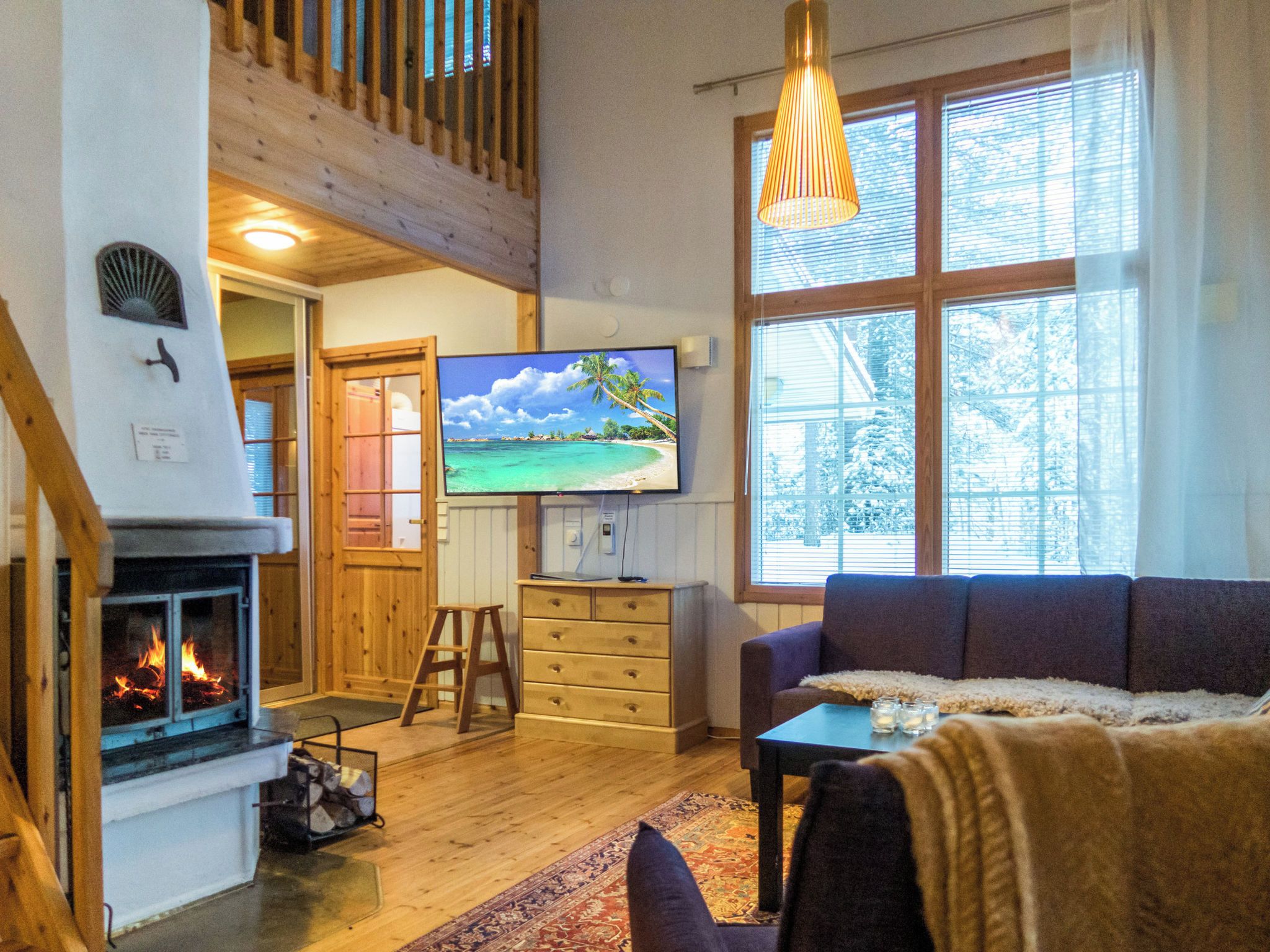 A cozy living room with a fireplace, a television, and a large window.