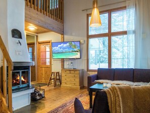 Una sala de estar acogedora con chimenea, televisor y un ventanal grande.