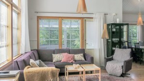 En stue med sofa, lænestol, sofabord og et spiseområde med stole og bord.