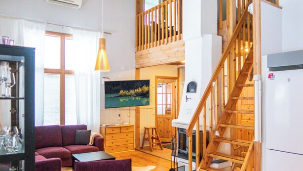 A spacious living area with a wooden staircase, a dining area, and a kitchen. - Katinkulma 2 by Interhome (Sotkamo)