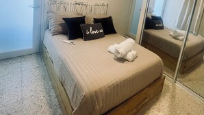 Un dormitorio con cama, mesita de noche, espejo y puerta.