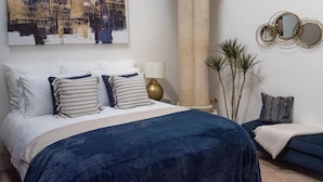 A bedroom with a bed, a large abstract painting, a column, a lamp, and a small plant. - The Nave a unique duplex apartment in a historic converted church near to beach. (Waterloo)
