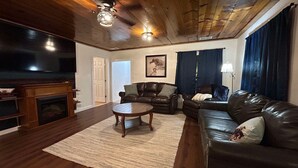 A living room with a fireplace, leather sofas, a coffee table, and a television. - Rodeo Ranch: Shuffleboard, Near seasonal Live Rodeo, Bunkbed, King Bed, SMOOR (Mansfield)