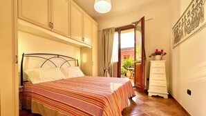 Ein Schlafzimmer mit Bett, Kommode und Blick ins Freie.
