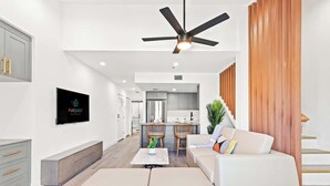 A modern living room with a sofa, a coffee table, and a TV mounted on the wall.