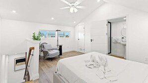 A modern bedroom with a large bed, a ceiling fan, a desk, and a chair. - Ocean Breeze 2C - Designer Loft & Beach Access (Panama City Beach)