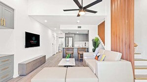 A modern living room with a sofa, a coffee table, and a TV mounted on the wall.