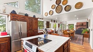Una cocina amplia con una isla grande, electrodomésticos de acero inoxidable y un comedor con chimenea de ladrillo.