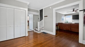 Un salon spacieux doté d’un plancher en bois, d’un escalier et d’un ventilateur de plafond.