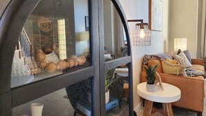 A modern living room with a curved glass partition, a sofa with cushions, a small round table, and a potted plant.