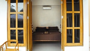 Una habitación con una cama, una silla y un ventanal con vistas a un coche y árboles.