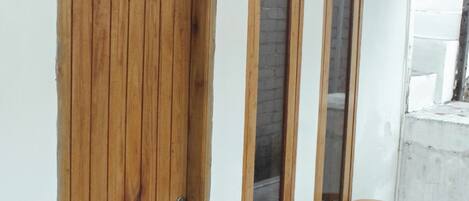 Una puerta de madera con un tirador de metal, tres ventanas verticales y un ventilador de techo.