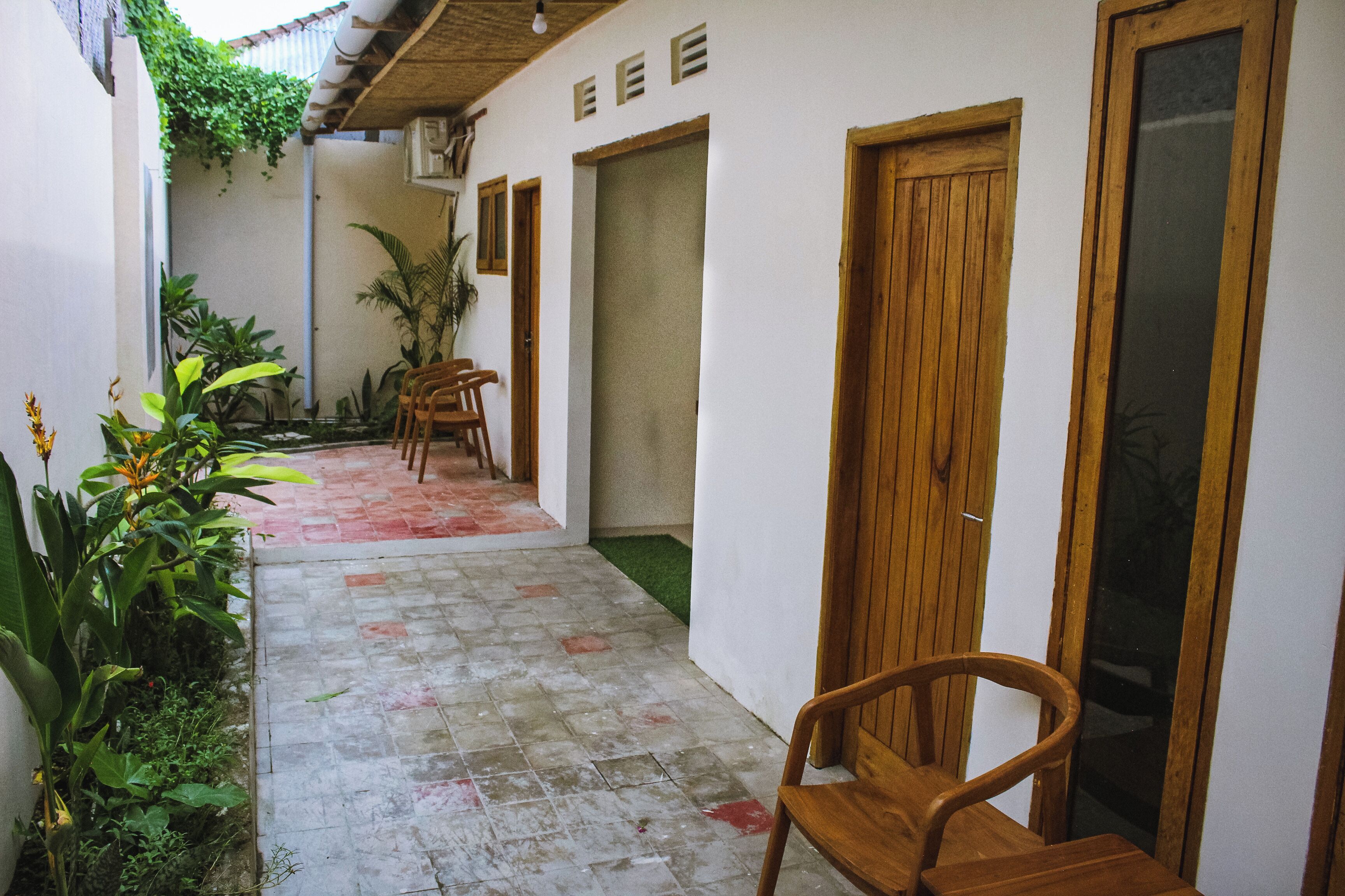 A narrow corridor with a tiled floor, wooden doors, and a chair.