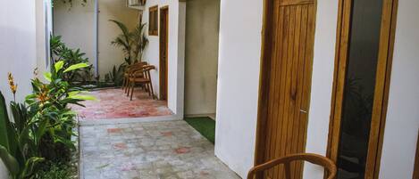 A narrow corridor with a tiled floor, wooden doors, and a chair.
