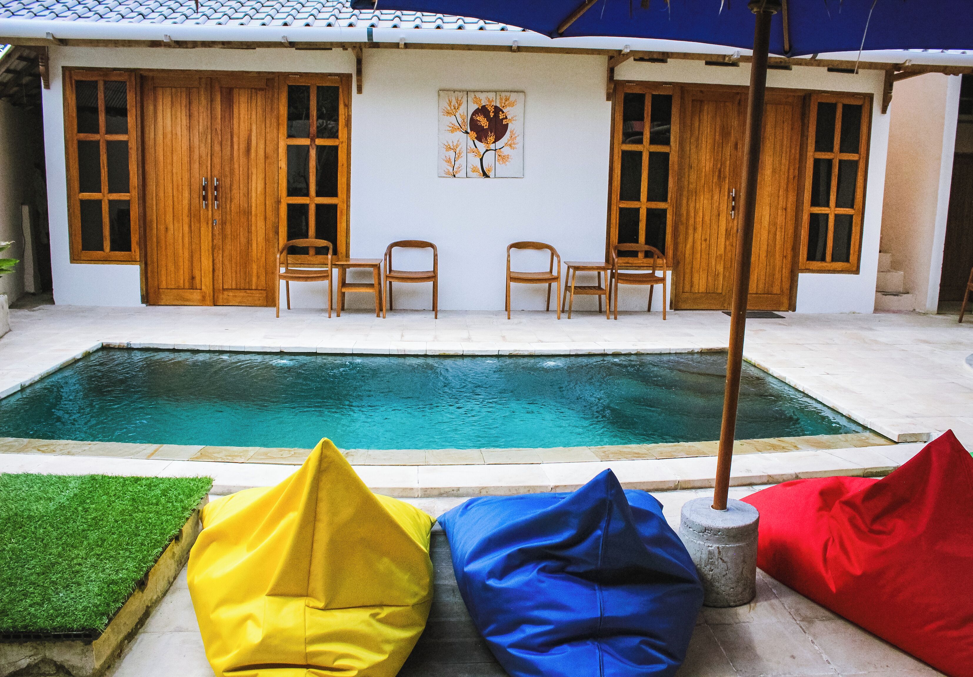 A poolside area with a wooden door, two chairs, and colorful bean bags.