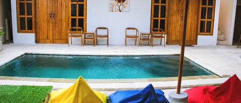 A poolside area with a wooden door, two chairs, and colorful bean bags.