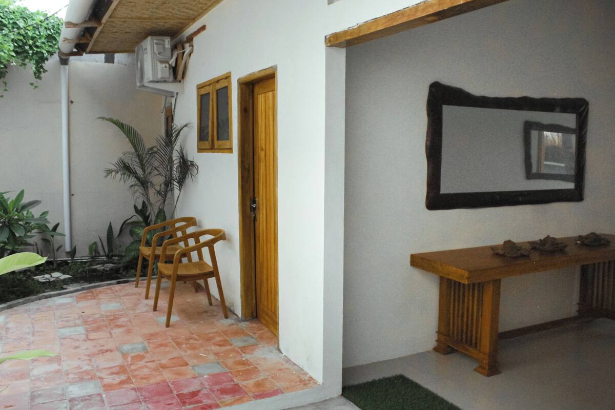 A small patio area with a tiled floor, a wooden bench, and two chairs.