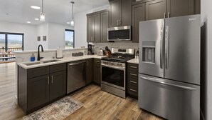A modern kitchen with dark cabinets, stainless steel appliances, a microwave, and a refrigerator. - Stunning Penthouse Breathtaking Water Views! 302 (Juneau)