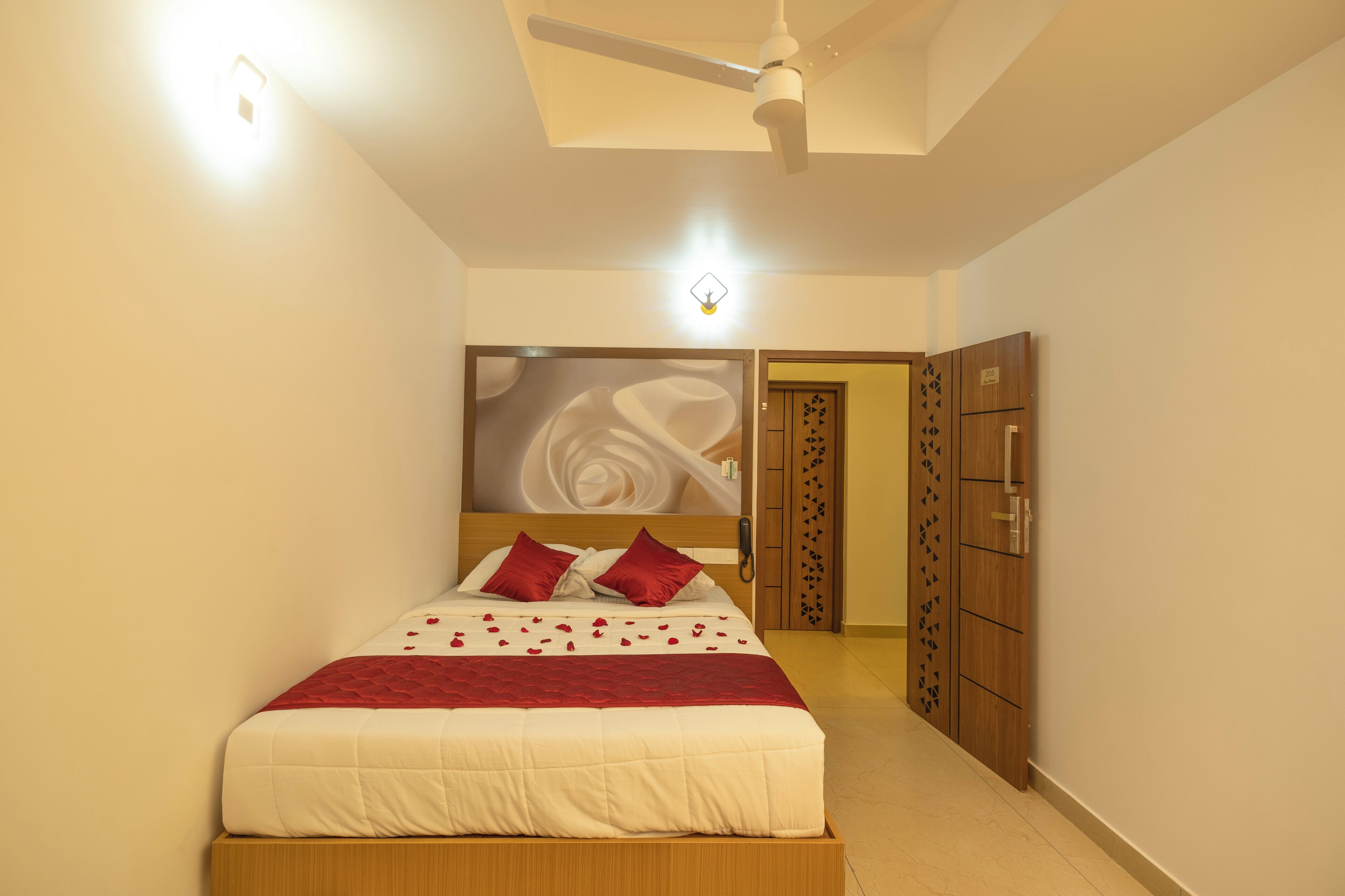 A bedroom with a bed, a ceiling fan, a wall-mounted light, and a wardrobe.