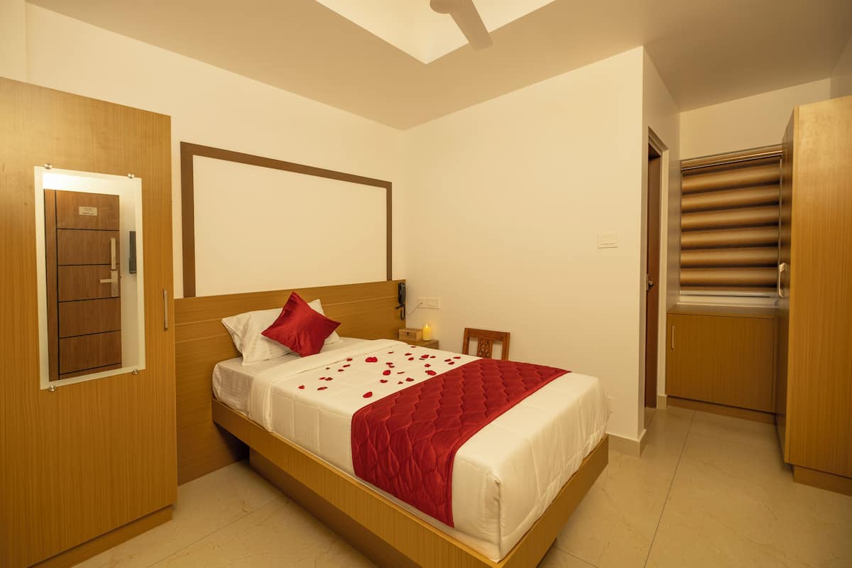A neatly arranged bedroom with a bed, wooden wardrobe, and a small table with a lamp.