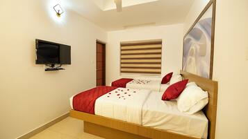 Un dormitorio con cama, televisor montado en la pared, ventana con persianas y ventilador de techo.