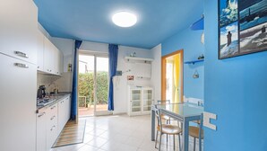 Una cocina moderna con armarios blancos, una estufa integrada y una zona de comedor con mesa y sillas.