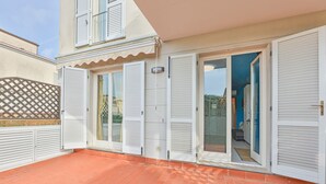 Un edificio con patio empedrado, contraventanas blancas y entrada protegida por un portón.