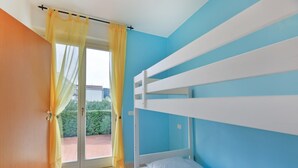 Una habitación con literas, una puerta corrediza de vidrio y vistas a un jardín.