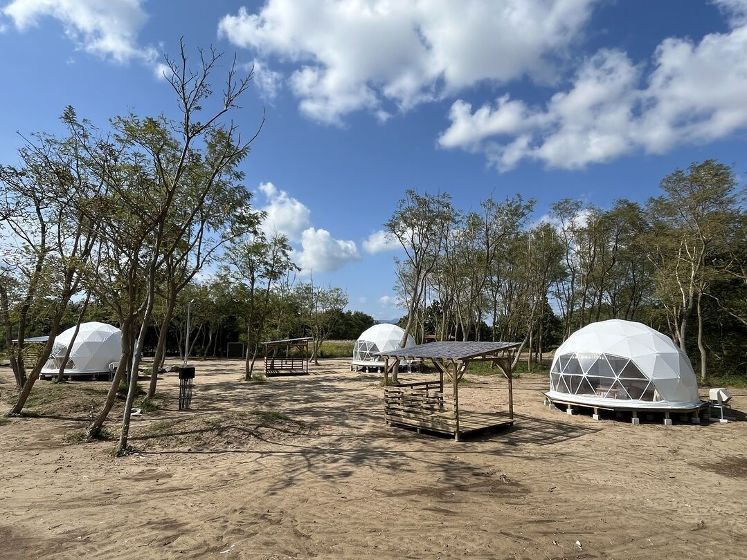 A campsite with dome-shaped tents, a wooden bench, and a fenced area.