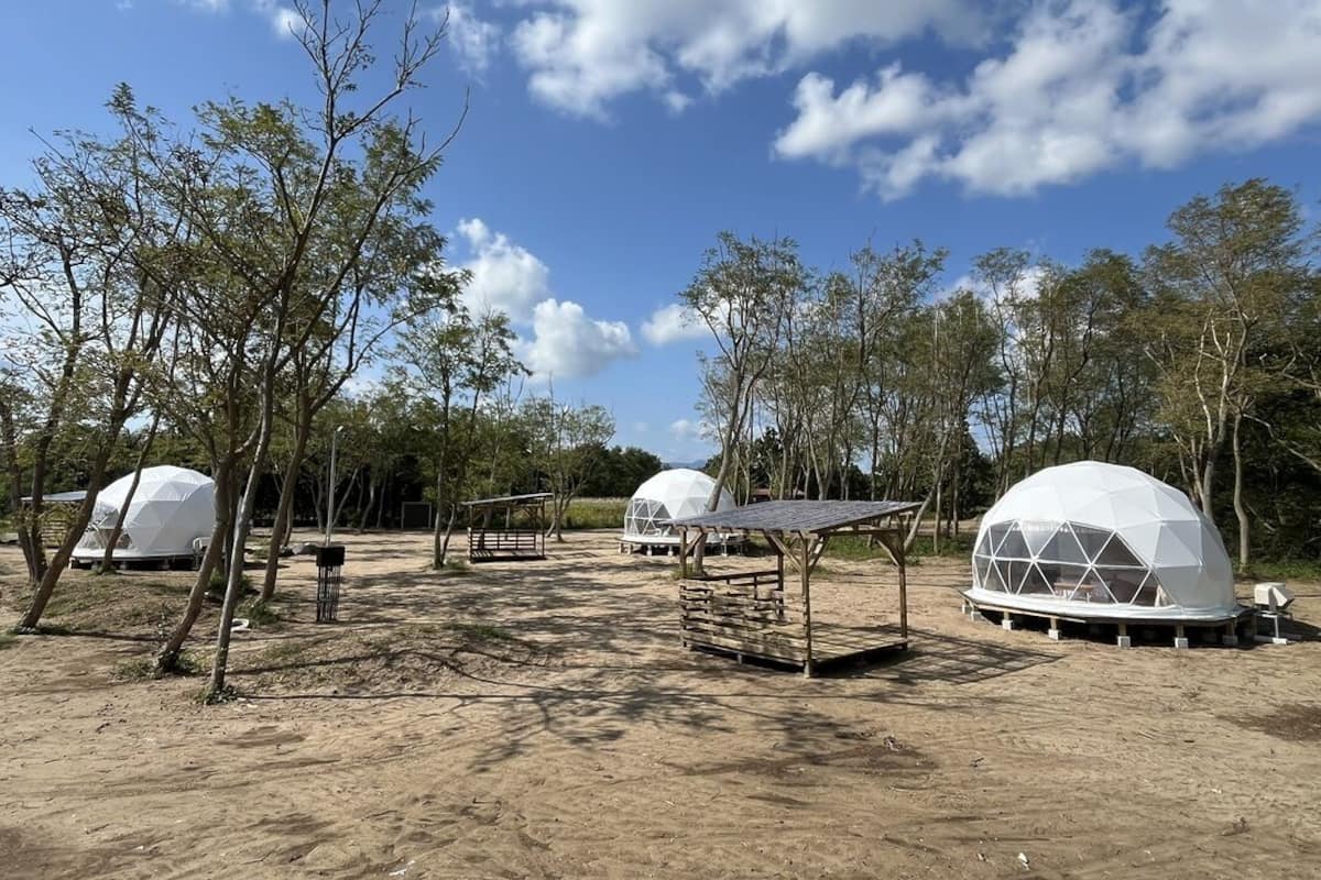 A campsite with dome-shaped tents, a wooden bench, and a fenced area.